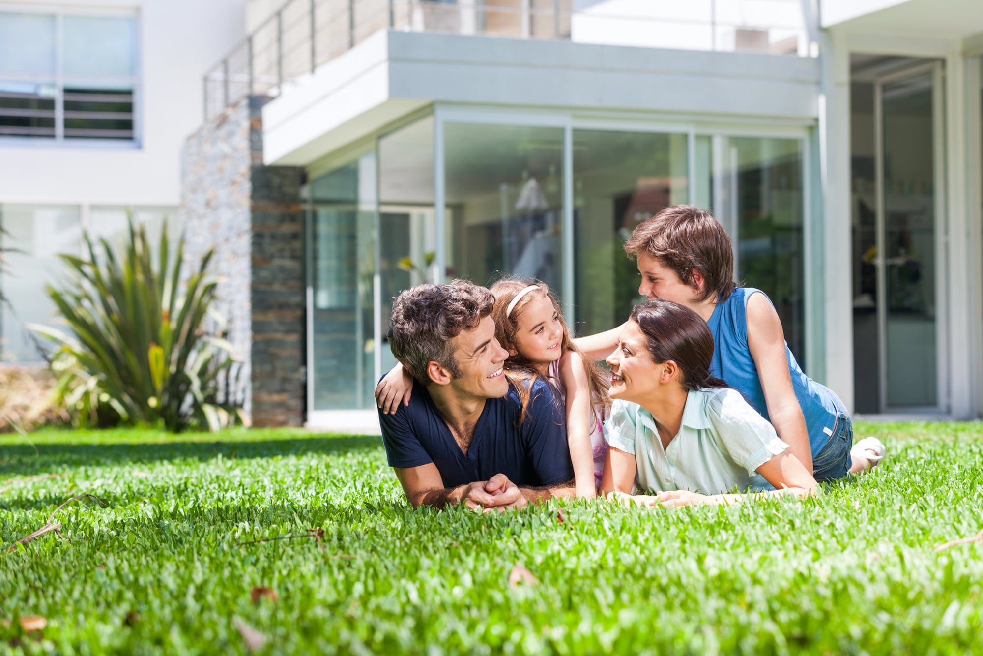 Happy family lying on lawn of new home following settlement in Perth. Happy family lying on lawn of new home following settlement in Perth.
